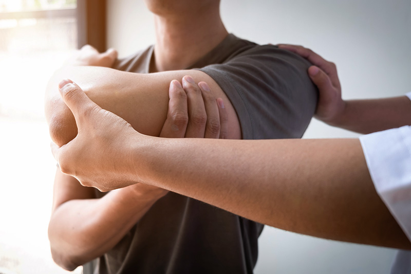 Two people engaging in physiotherapy, with one person's hands adjusting the other's arm.