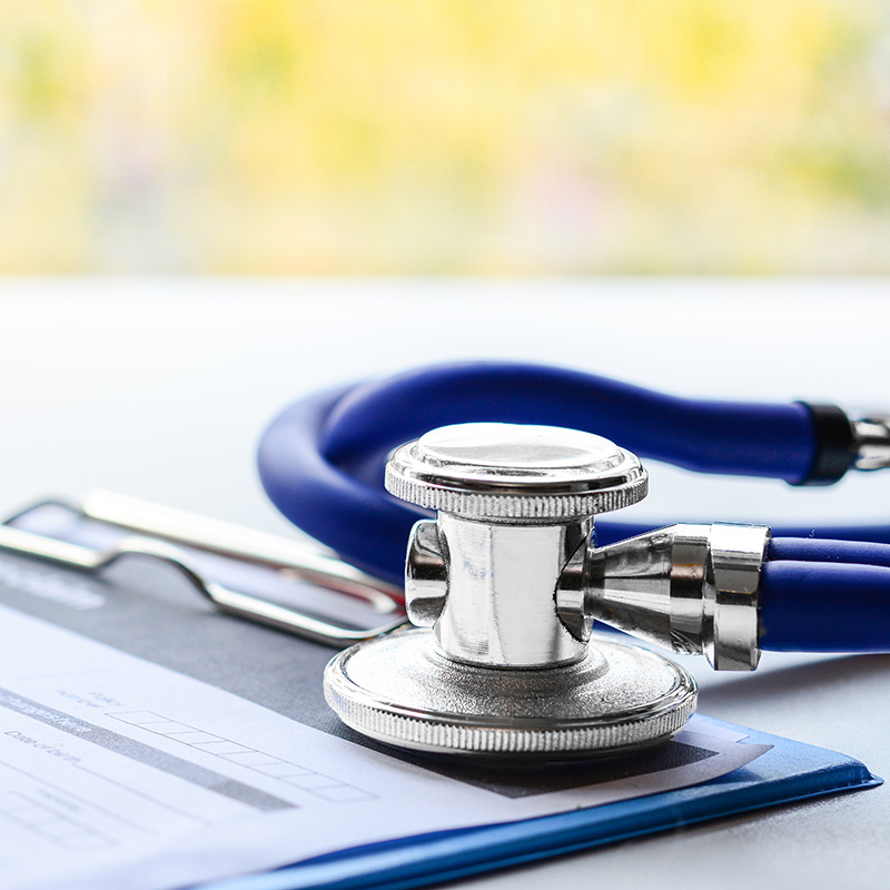 nurse-stethescope-paperwork A silver stethoscope with blue tubing rests on a medical clipboard with a form.